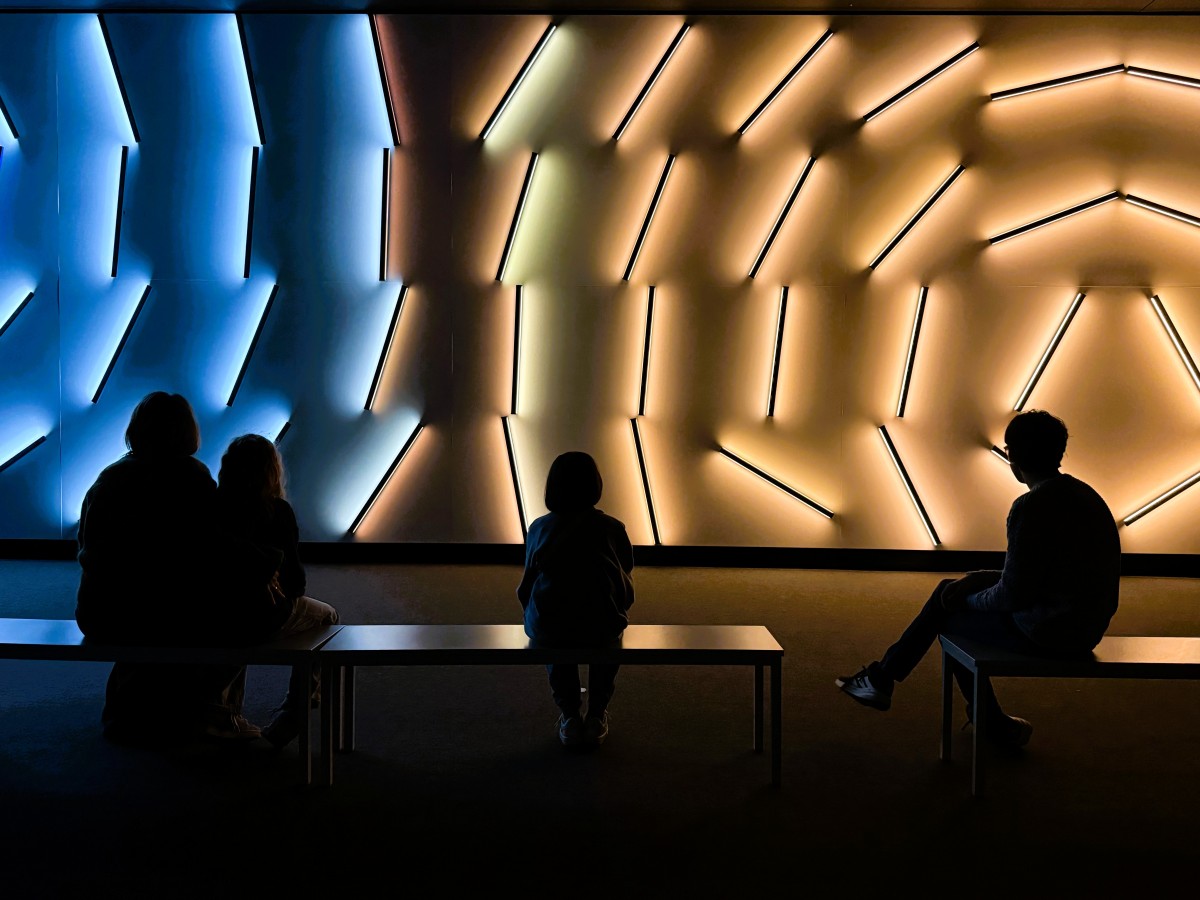 Family admires the large-scale art installation of moving light rods at Signal Space Prague