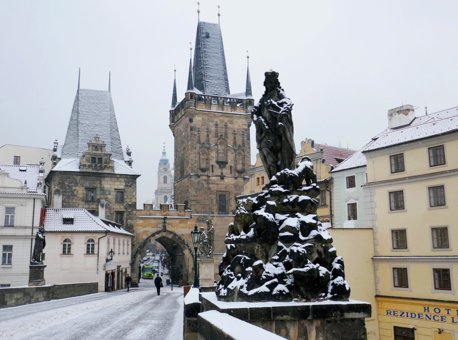 Walking across Prague's romantic Charles Bridge in the snow. One of the many festive things to do in Prague in December. The Little Adventurer.