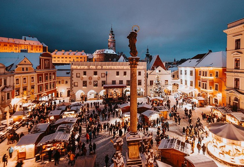 Snowy scene in Český Krumlov's main square with a busy Christams market, featuring a tradional carousel - Things to do in Český Krumlov with kids