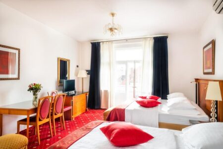 A bright room with two double beds, a desk and television in Hotel Leon D'Oro - one of the best family-friendly hotels in Prague. The Little Adventurer