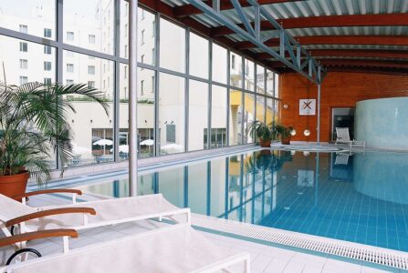 An indoor swimming pool, with sound loungers scattered around the edge at the Novotel Praha Wenceslas Square - one of the best family-friendly hotels in Prague. 
