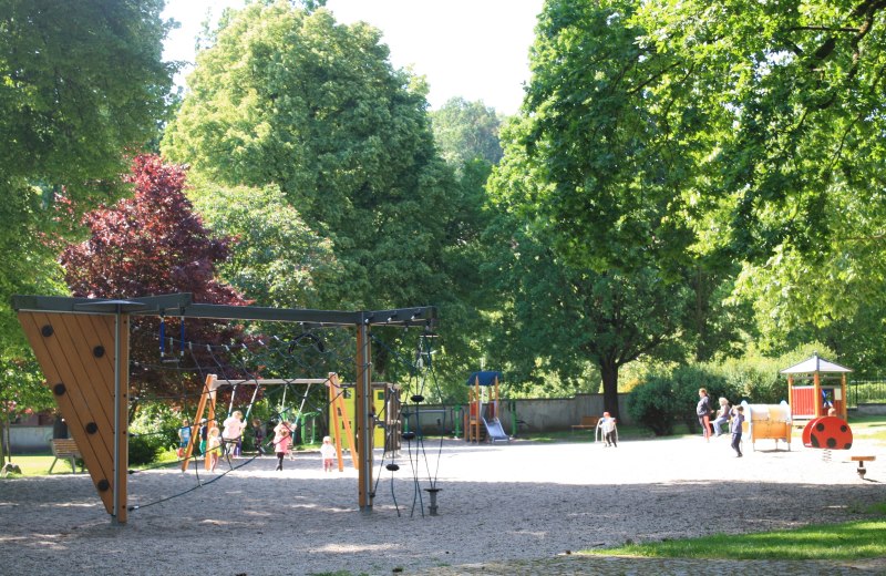 Children playing on climbing frames,swings and mini roundabout at Cesky Krumlov city park