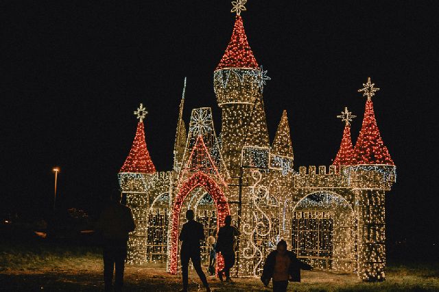 People stood outside a large castle made of fairy lights at Lumina Park Prague