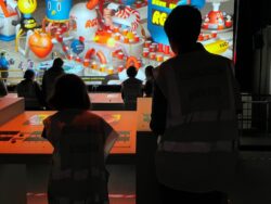 Silloette of people pressing buttons in front of large screen at Factory International