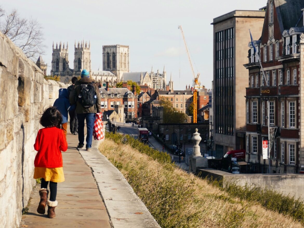 A small child walks along York's medieval walls outside The Grand Hotel with the York Minister in the background