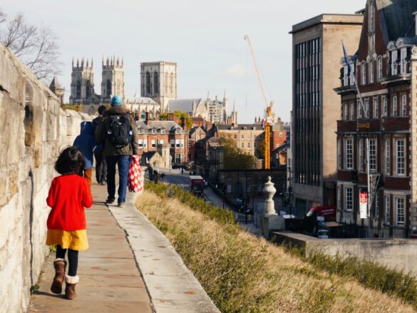 A small child walks along York's medieval walls outside The Grand Hotel with the York Minister in the background
